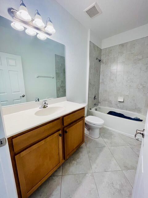 bathroom featuring toilet, bathing tub / shower combination, visible vents, and tile patterned floors