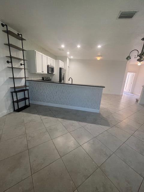 956 NE Trailside Run, Port Saint Lucie, FL 34983 - kitchen featuring fridge, stainless steel microwave, recessed lighting, a peninsula, and white cabinets