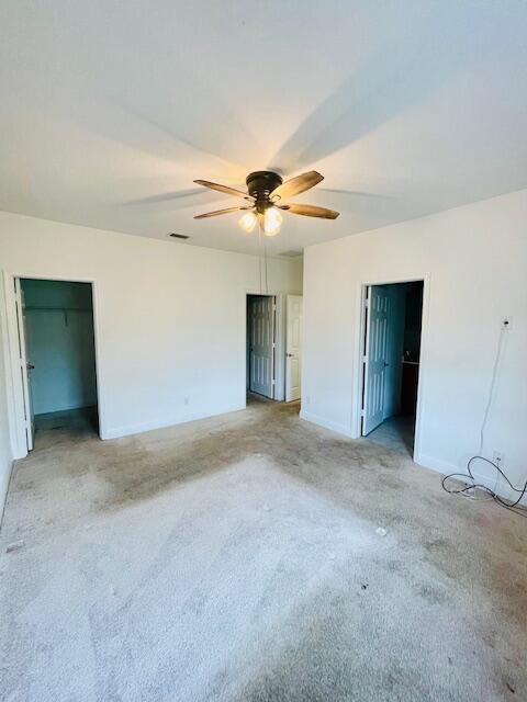 unfurnished bedroom featuring ceiling fan, a spacious closet, visible vents, and baseboards