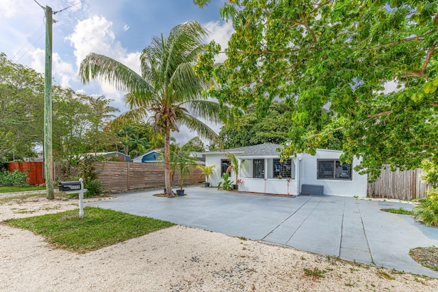 view of front of property featuring driveway, fence, and stucco siding