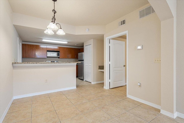 kitchen featuring a textured ceiling, freestanding refrigerator, a peninsula, and visible vents