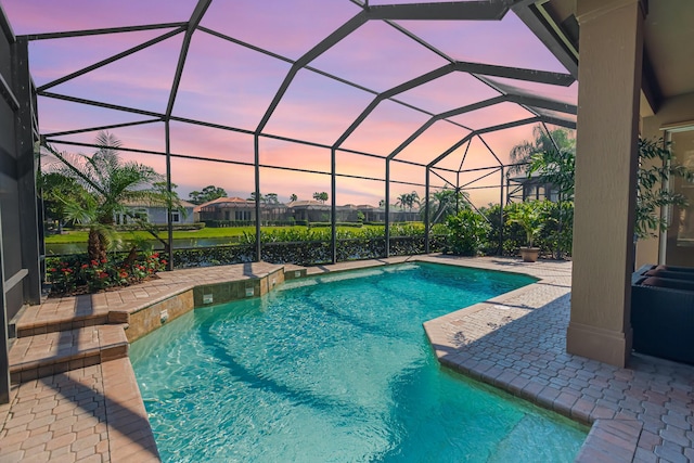 pool at dusk with a patio area and an outdoor pool
