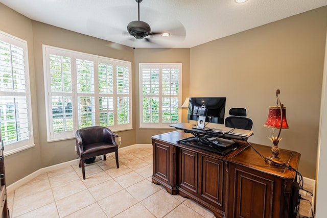 home office featuring a ceiling fan, baseboards, a healthy amount of sunlight, and light tile patterned floors