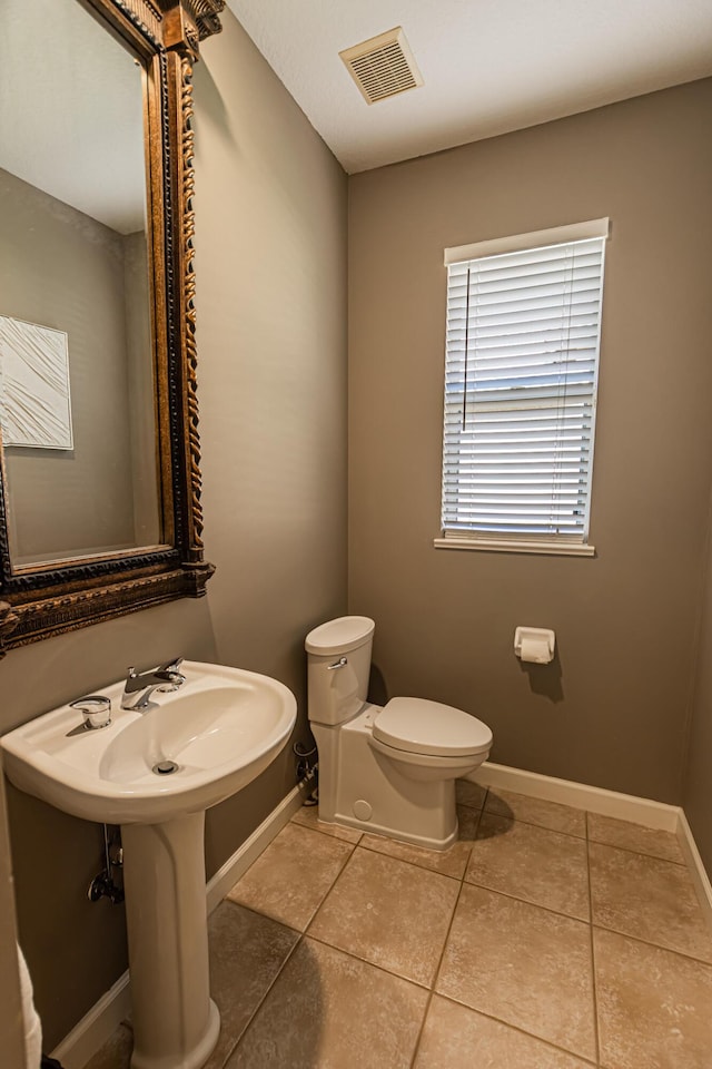 half bath with tile patterned floors, toilet, visible vents, and baseboards