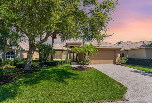 obstructed view of property with a yard, a garage, stucco siding, and driveway