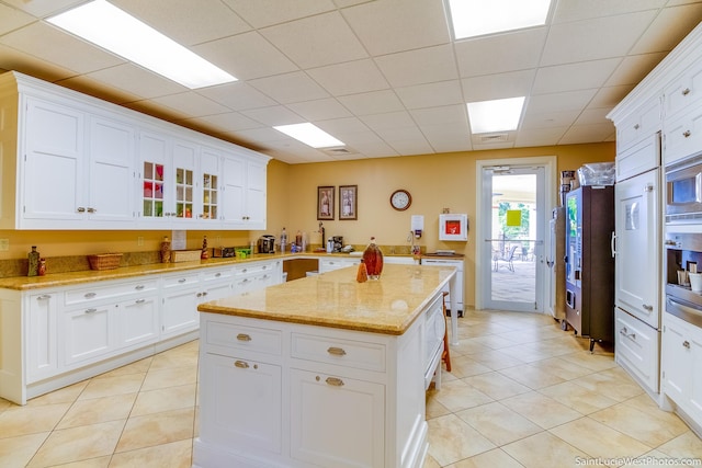 kitchen with white cabinets, light tile patterned flooring, and a center island