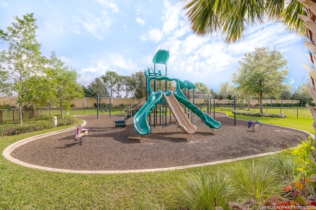 communal playground featuring a lawn and fence