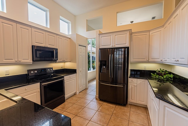 kitchen featuring black refrigerator with ice dispenser, light tile patterned floors, electric range oven, a towering ceiling, and white cabinets