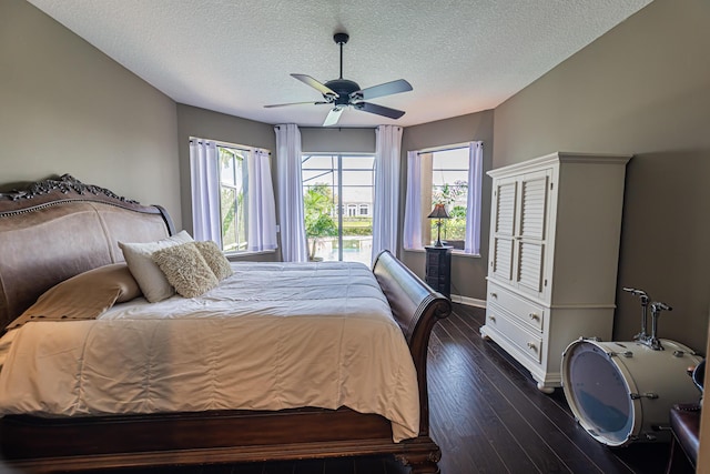 bedroom featuring multiple windows, a textured ceiling, dark wood-type flooring, and baseboards