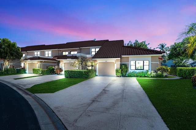 view of front facade featuring stucco siding, a tile roof, concrete driveway, and a yard