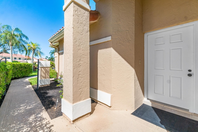 view of exterior entry featuring a tiled roof and stucco siding