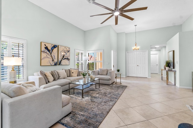 living room with light tile patterned floors, visible vents, baseboards, a towering ceiling, and ceiling fan with notable chandelier