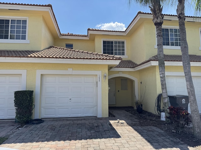 multi unit property featuring decorative driveway, an attached garage, and stucco siding