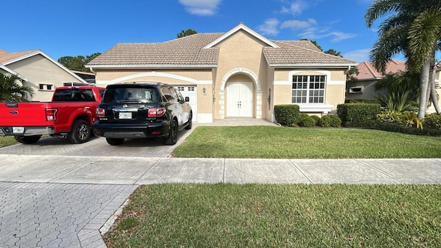 mediterranean / spanish home featuring a garage, concrete driveway, a tiled roof, a front yard, and stucco siding