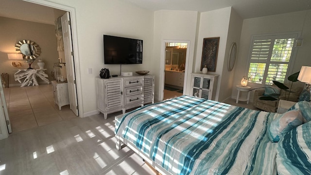 bedroom with light wood-type flooring, baseboards, and connected bathroom