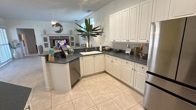 kitchen with appliances with stainless steel finishes, dark countertops, a sink, and a peninsula