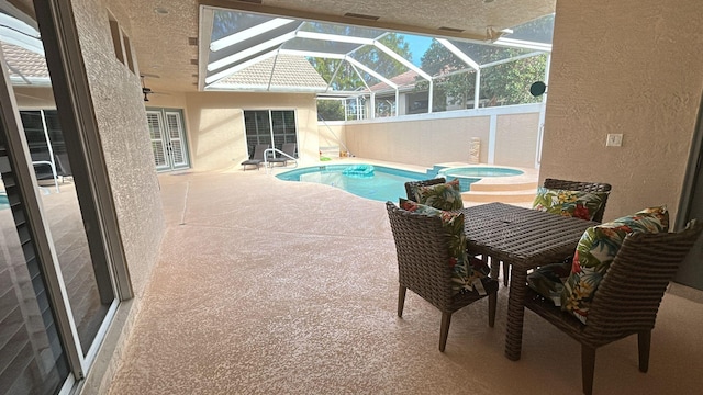 view of swimming pool with a pool with connected hot tub, glass enclosure, and a patio