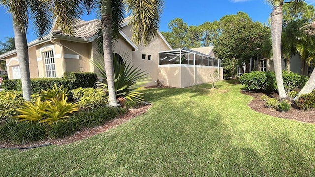 view of yard featuring an attached garage and glass enclosure