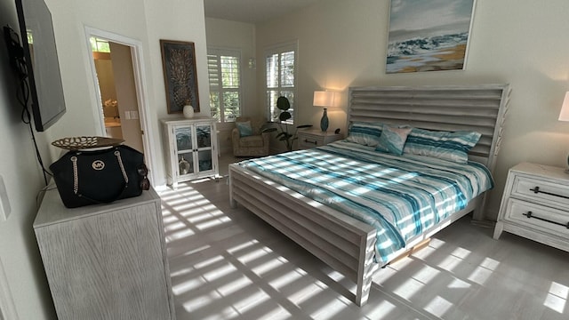 bedroom with ensuite bath and wood finished floors