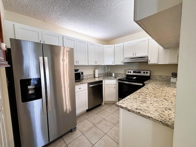 kitchen featuring light tile patterned floors, stainless steel appliances, white cabinets, a sink, and under cabinet range hood