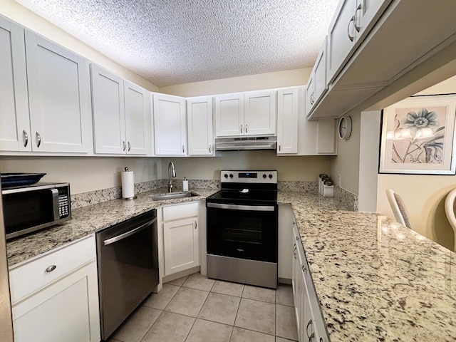 kitchen with a textured ceiling, light tile patterned flooring, under cabinet range hood, a sink, and appliances with stainless steel finishes