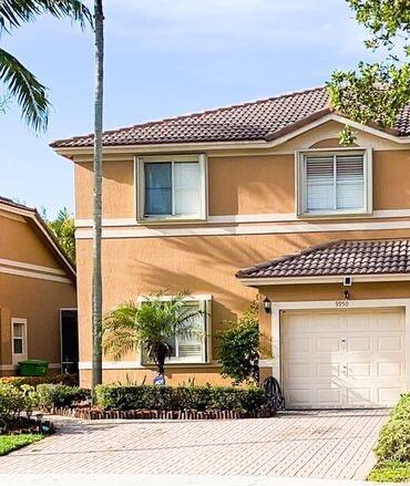 view of front facade with decorative driveway, an attached garage, a tile roof, and stucco siding