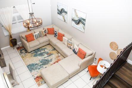 living room featuring baseboards, stairway, a notable chandelier, and tile patterned floors