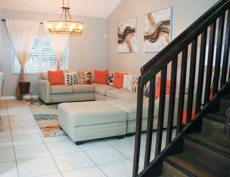 living room featuring lofted ceiling, an inviting chandelier, and tile patterned flooring