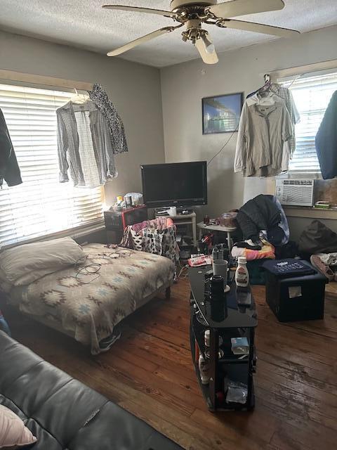 interior space with a textured ceiling, ceiling fan, wood-type flooring, and cooling unit