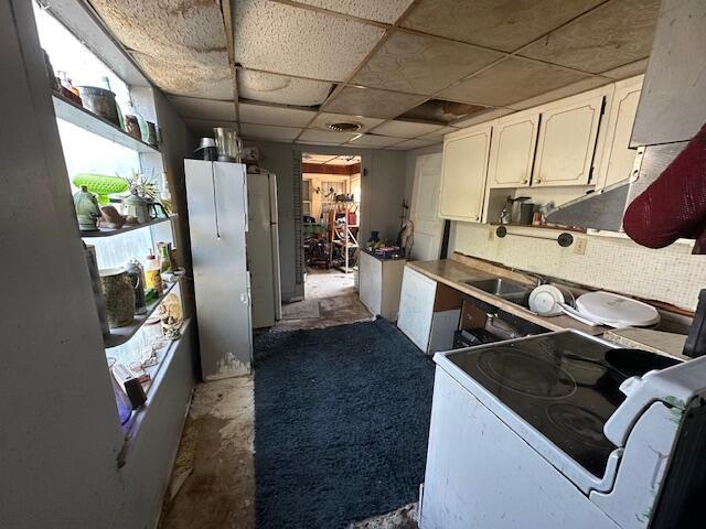 kitchen featuring white appliances, white cabinets, and a drop ceiling