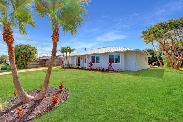 single story home with metal roof, a front yard, fence, and stucco siding