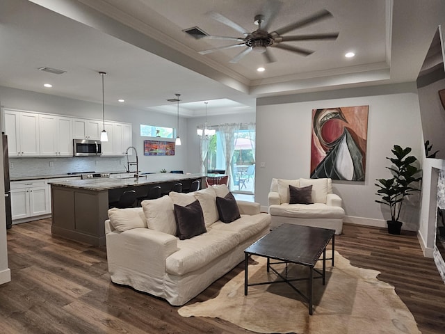 living area with recessed lighting, visible vents, dark wood-style floors, a raised ceiling, and crown molding