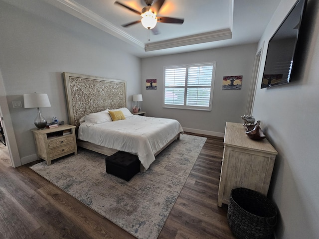 bedroom with dark wood-style floors, a tray ceiling, crown molding, and baseboards