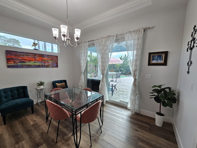 dining room featuring a raised ceiling, ornamental molding, wood finished floors, a chandelier, and baseboards