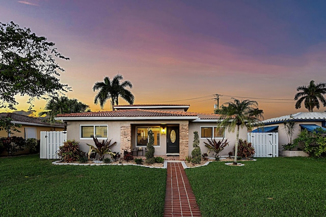 view of front of home featuring a gate, fence, a front lawn, and stucco siding