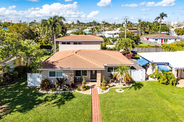 mediterranean / spanish-style home featuring a front yard, a tile roof, a fenced backyard, and stucco siding