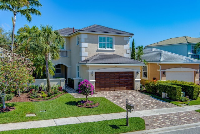 view of front of home with a tile roof, a front lawn, decorative driveway, and stucco siding