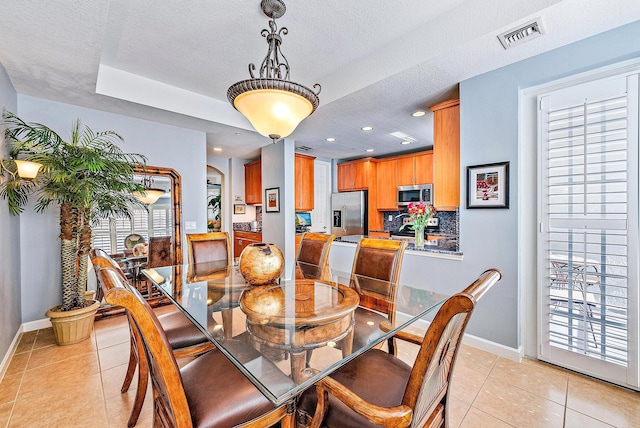 dining space featuring light tile patterned floors, visible vents, arched walkways, and a textured ceiling