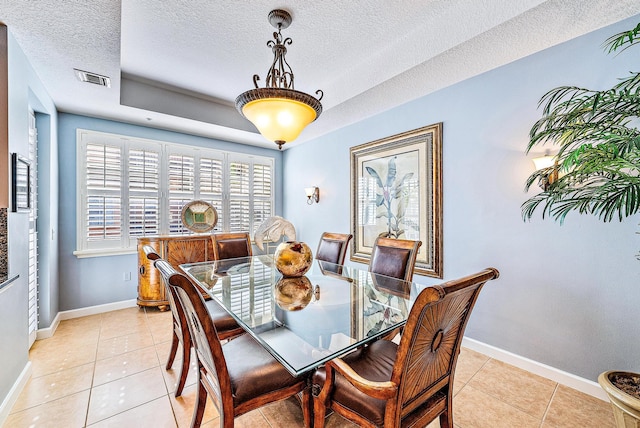 dining space with light tile patterned floors, a textured ceiling, visible vents, and baseboards