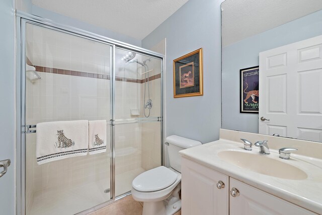 bathroom with a stall shower, toilet, tile patterned flooring, a textured ceiling, and vanity