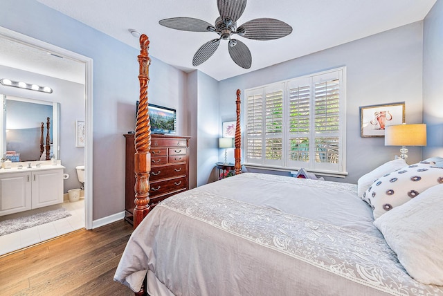 bedroom with a ceiling fan, baseboards, ensuite bathroom, and wood finished floors