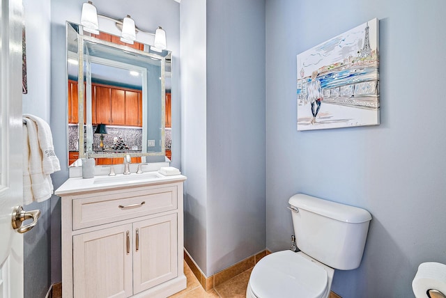 half bath featuring tile patterned flooring, vanity, toilet, and baseboards