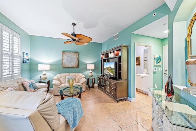 living room with a ceiling fan, visible vents, baseboards, and light tile patterned floors