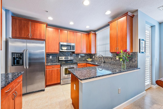 kitchen featuring light tile patterned floors, backsplash, appliances with stainless steel finishes, a sink, and dark stone counters