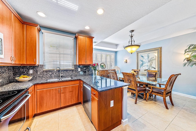 kitchen with brown cabinets, appliances with stainless steel finishes, light tile patterned flooring, a sink, and a peninsula