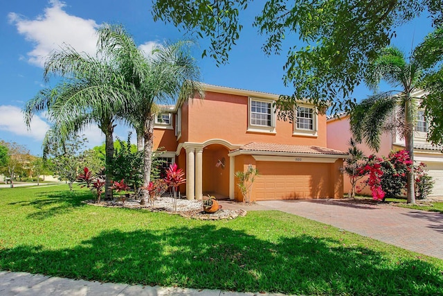 mediterranean / spanish-style home featuring decorative driveway, stucco siding, a front yard, a garage, and a tiled roof