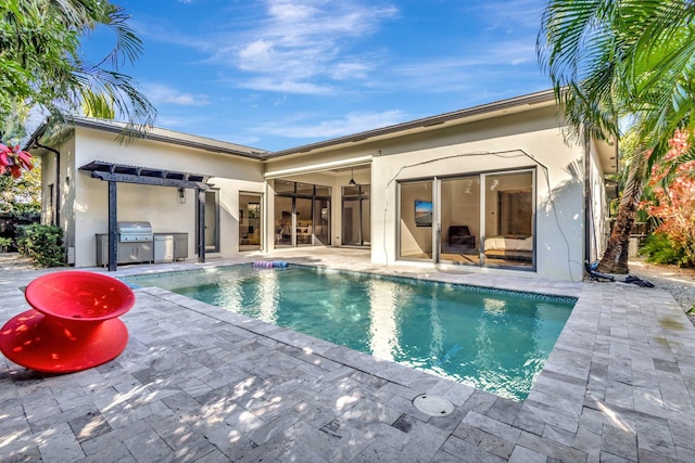 rear view of house with a patio area, an outdoor kitchen, an outdoor pool, and stucco siding