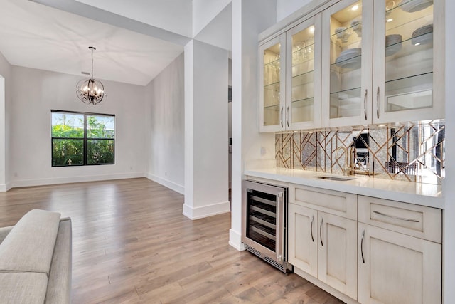 bar with light wood finished floors, wine cooler, baseboards, and decorative backsplash