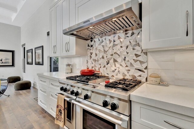 kitchen with light countertops, backsplash, white cabinets, ventilation hood, and double oven range