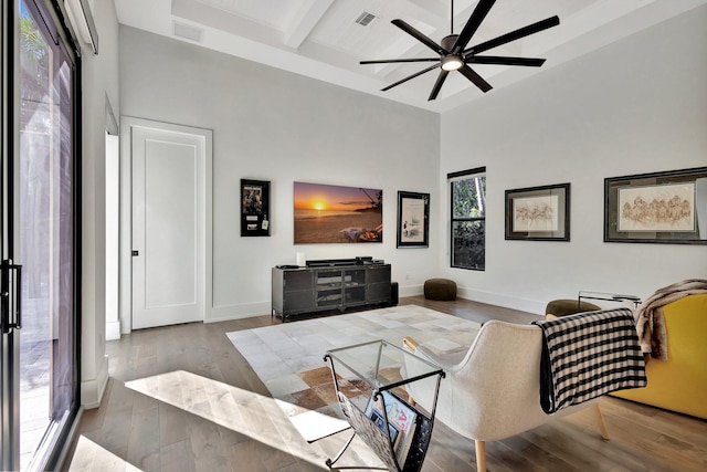 living room with visible vents, beamed ceiling, a towering ceiling, and wood finished floors